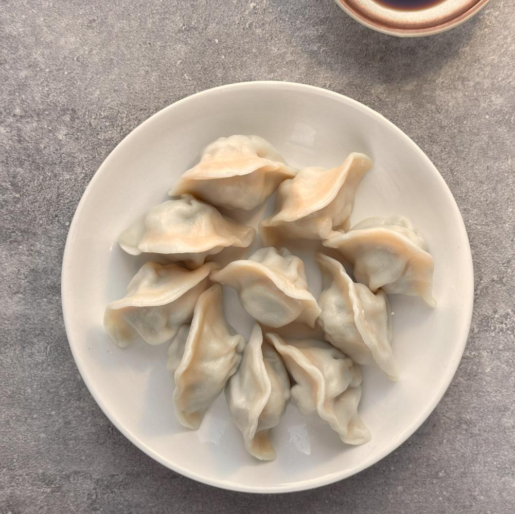 Handmade Chinese dumplings served on a white plate, freshly prepared by Healthy7 Meals.